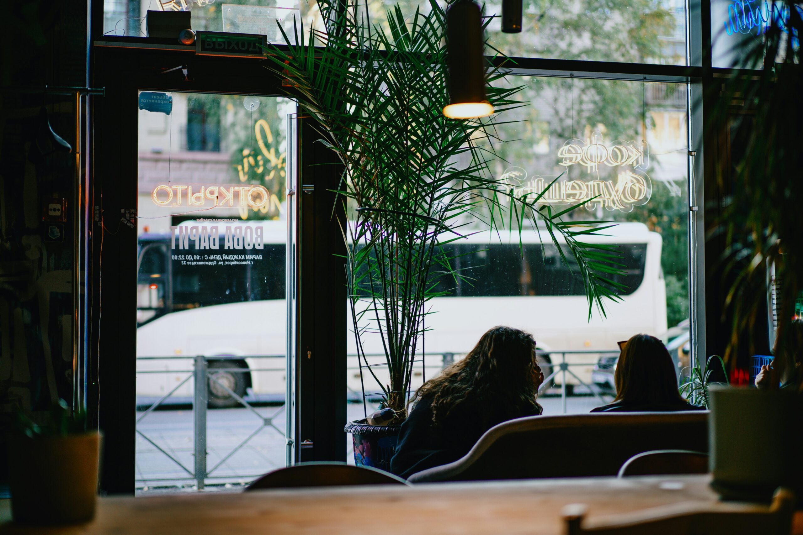 Two friends talking about side hustles for recent grads over coffee at a warmly lit café table
