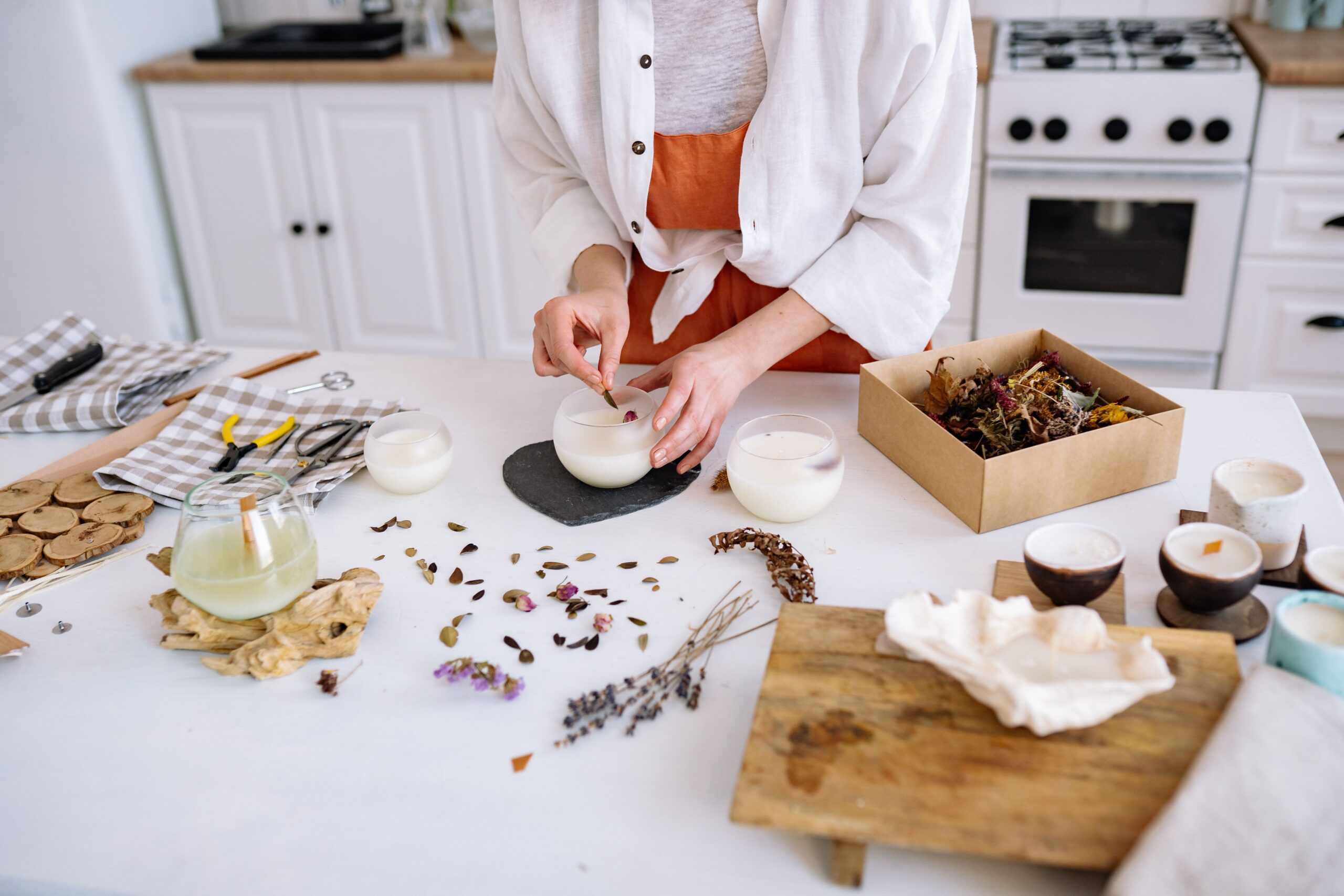 Candle making side hustle: artisan hand-pouring and decorating a soy candle with dried lavender