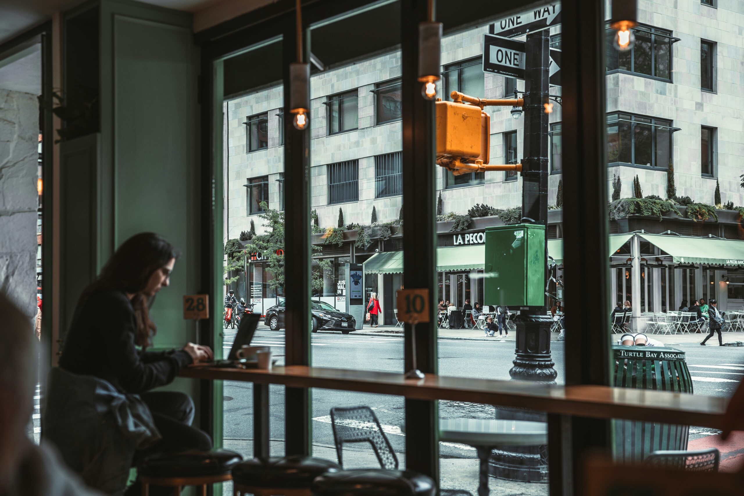 A remote worker working on a laptop in a cozy cafe to escape the 9 to 5