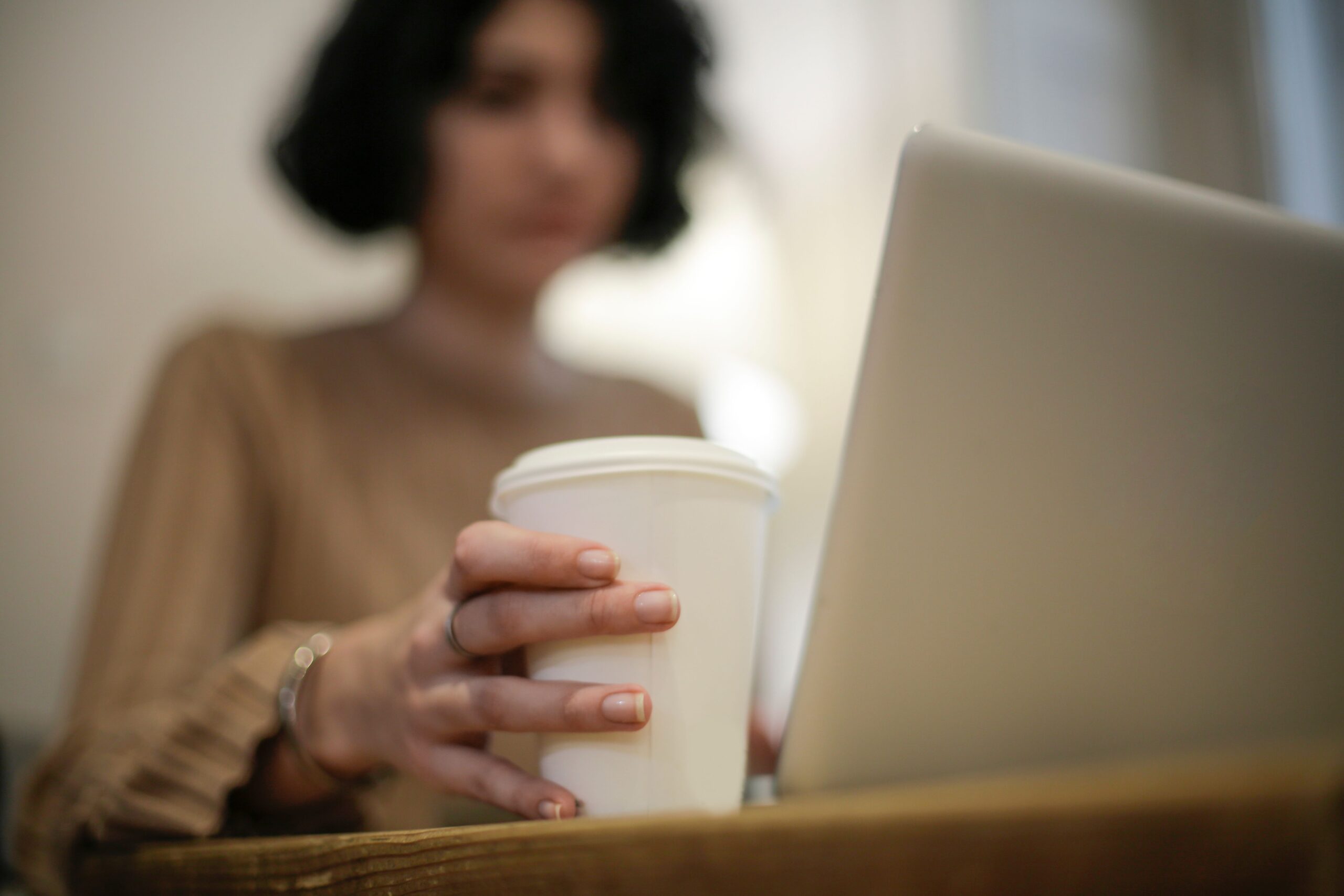 Freelancer working on a laptop with coffee, illustrating side hustle taxes when you also have a full-time job